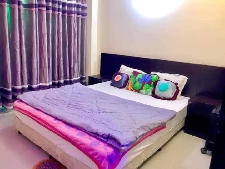 Schlafzimmer mit einem Bett mit lila Bettwäsche und Kissen in der Unterkunft World Beach Resort in Kelātali