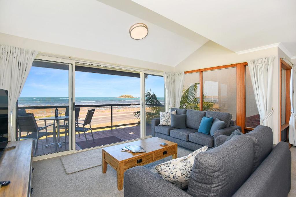 a living room with a couch and a view of the ocean at Granite Views Beachfront Apartment + WiFi in Encounter Bay
