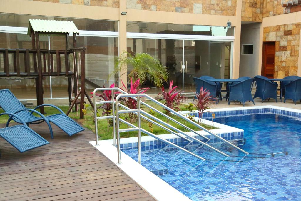 a swimming pool with blue chairs next to a building at House Aconchegante Ponta Negra in Natal