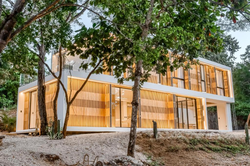 une maison avec des murs en verre et des arbres dans l'établissement Casa Sabor a Mar, à Playa Conchal