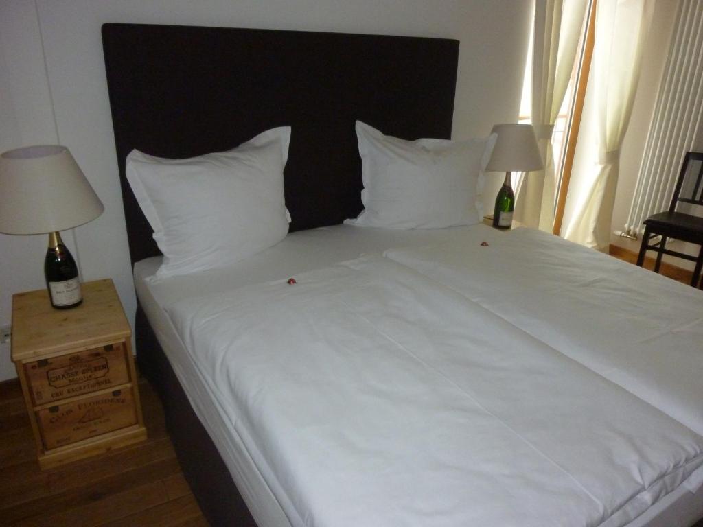 een groot wit bed met 2 lampen op een nachtkastje bij Landgasthof Zum Hasen in Kleinwallstadt