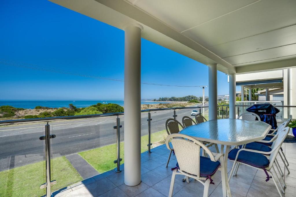 a balcony with a table and chairs and a view of the ocean at Esplanade Beachfront Victor Harbor in Victor Harbor