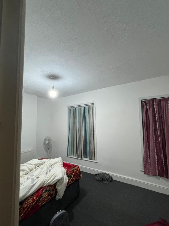 um quarto branco com uma cama e 2 janelas em 241 albert avenue em Hull