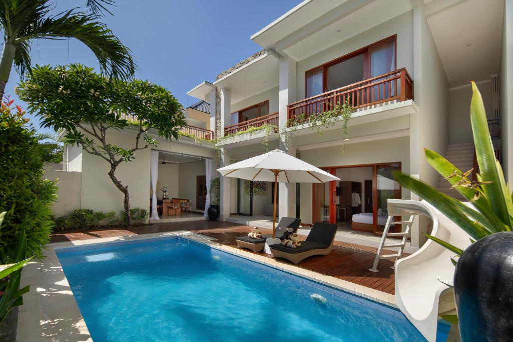 a villa with a swimming pool and a house at Daha Mansions Seminyak in Seminyak