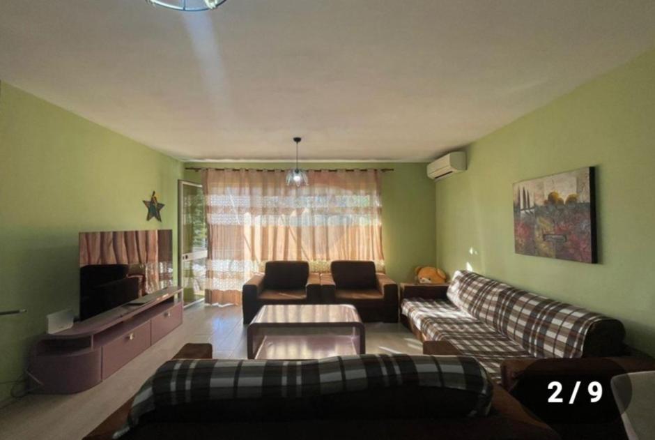 een woonkamer met een bank en een tv bij Ohana Apartments in Tirana