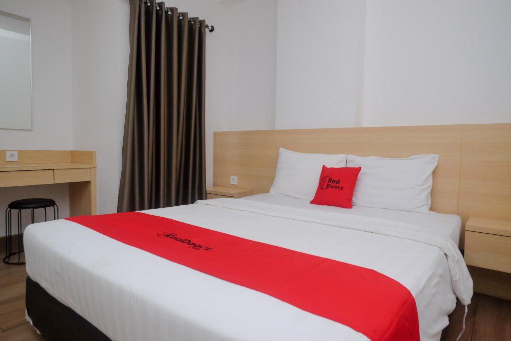 una camera da letto con un grande letto con cuscini rossi di RedDoorz Apartment near Exit Toll Colomadu a Solo