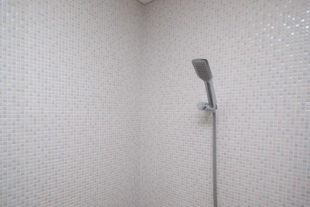una doccia in un angolo con una parete di piastrelle bianche di RedDoorz Apartment near Exit Toll Colomadu a Solo