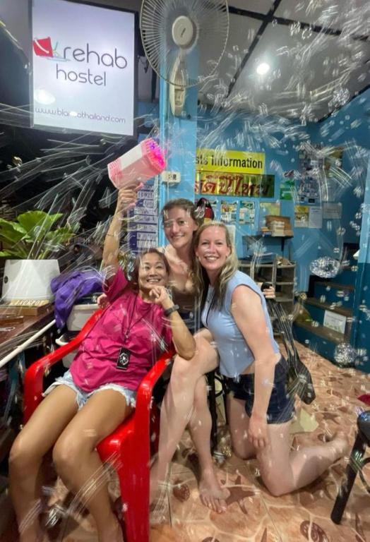 un grupo de personas sentadas en una silla en una tienda en Rehab Hostel, en Islas Phi Phi