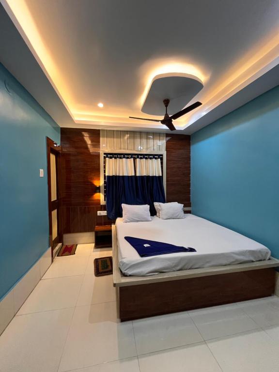 um quarto com uma cama e uma parede azul em Hotel Holiday Home em Digha