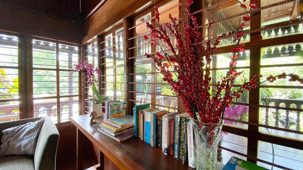 Cette chambre comprend une table avec des livres et un vase de fleurs. dans l'établissement rumah kayu sulawesi antique, à Bedugul
