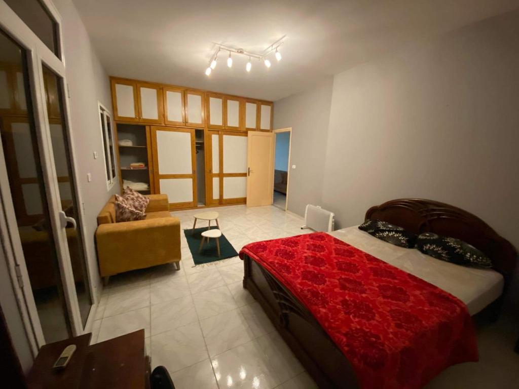 een slaapkamer met een rood bed en een bank bij S+2 Corniche Nord in Bizerte