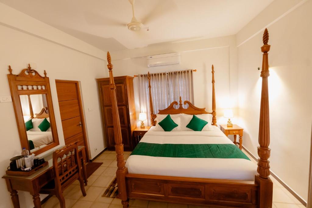 ein Schlafzimmer mit einem großen Bett und einem Spiegel in der Unterkunft SeaCoast Inn FortKochi in Fort Kochi