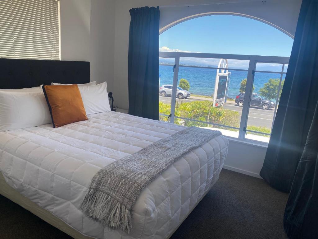 a bedroom with a bed with a view of the ocean at Lakeside Taupo Motel in Taupo