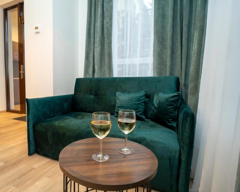 two glasses of wine sitting on a table in front of a couch at Central Station Apartment No1 in Kaunas