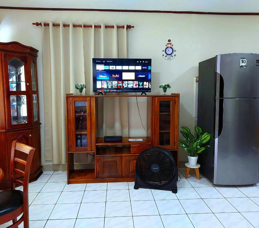 ein Wohnzimmer mit einem TV und einem Kühlschrank in der Unterkunft Casa equipada en el centro de Puntarenas in Puntarenas