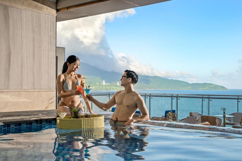 a man and a woman sitting in a swimming pool at BlueSun Danang Beach Hotel in Da Nang