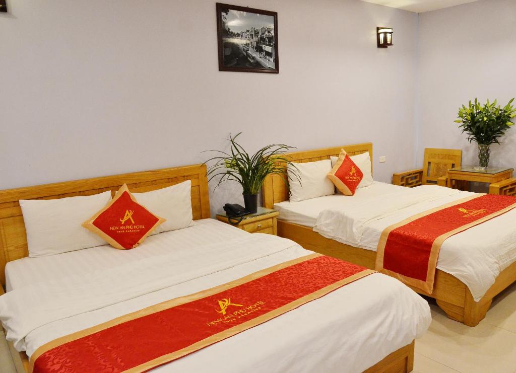 1 dormitorio con 2 camas con sábanas rojas y blancas en New An Phú Hotel, en Dong Anh