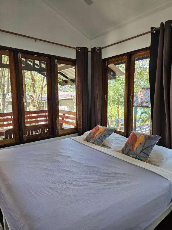 a bedroom with a large white bed with windows at Horizon Resort in Ko Samed