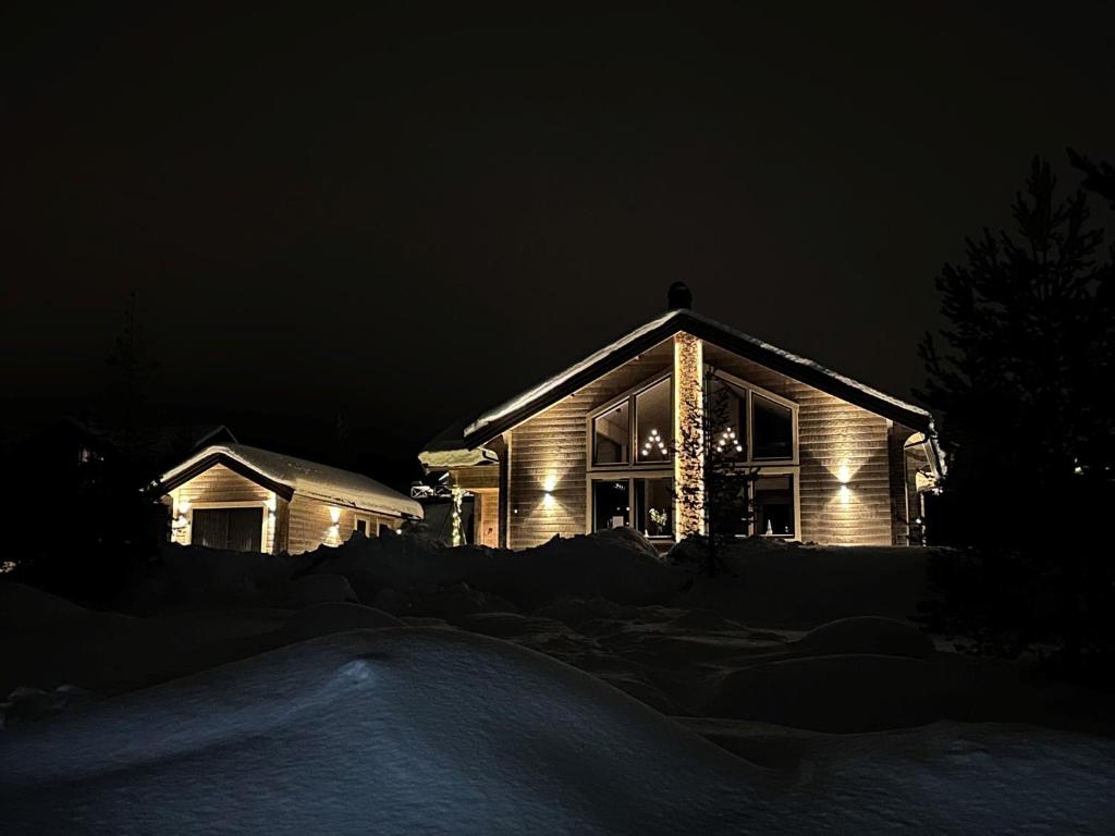 Una casa iluminada por la noche en la nieve en Vinterdröm Idre Himmelfjäll, en Idre