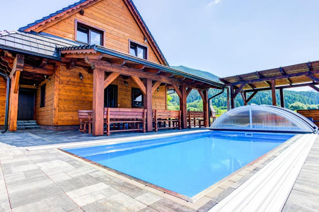 a house with a swimming pool in front of a building at Drevenica pod Sitieňom 2 in Svätý Kríž