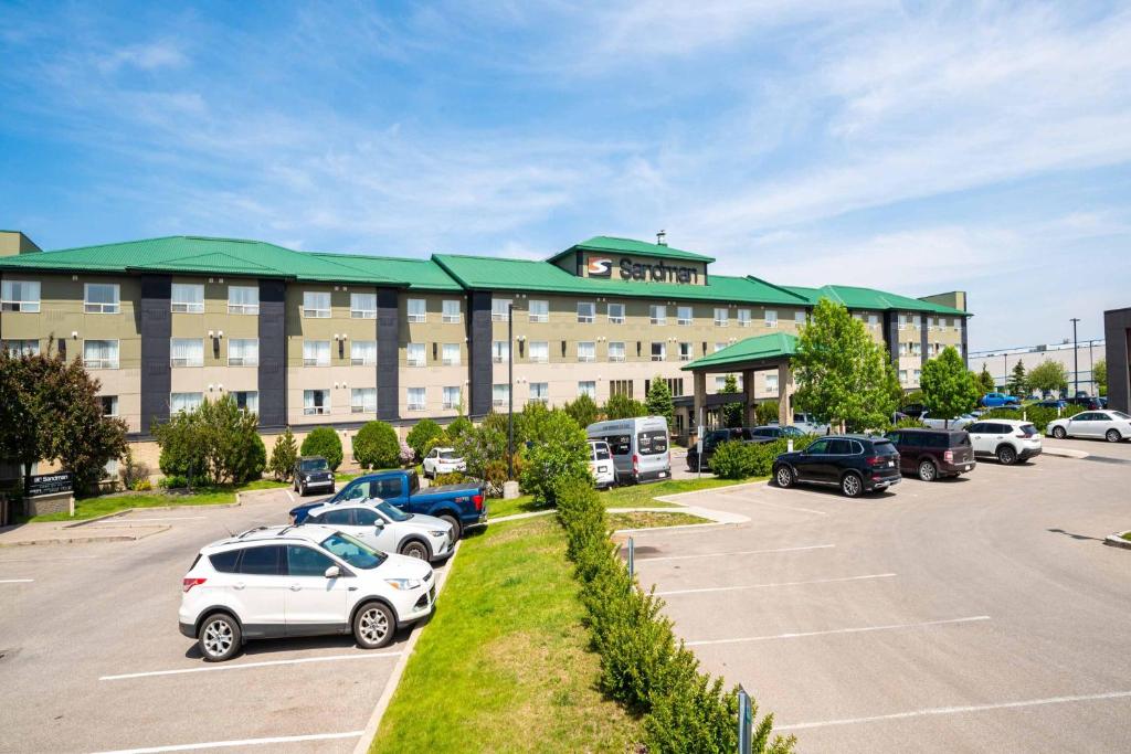 un hotel con coches estacionados en un estacionamiento en Sandman Hotel Calgary Airport en Calgary