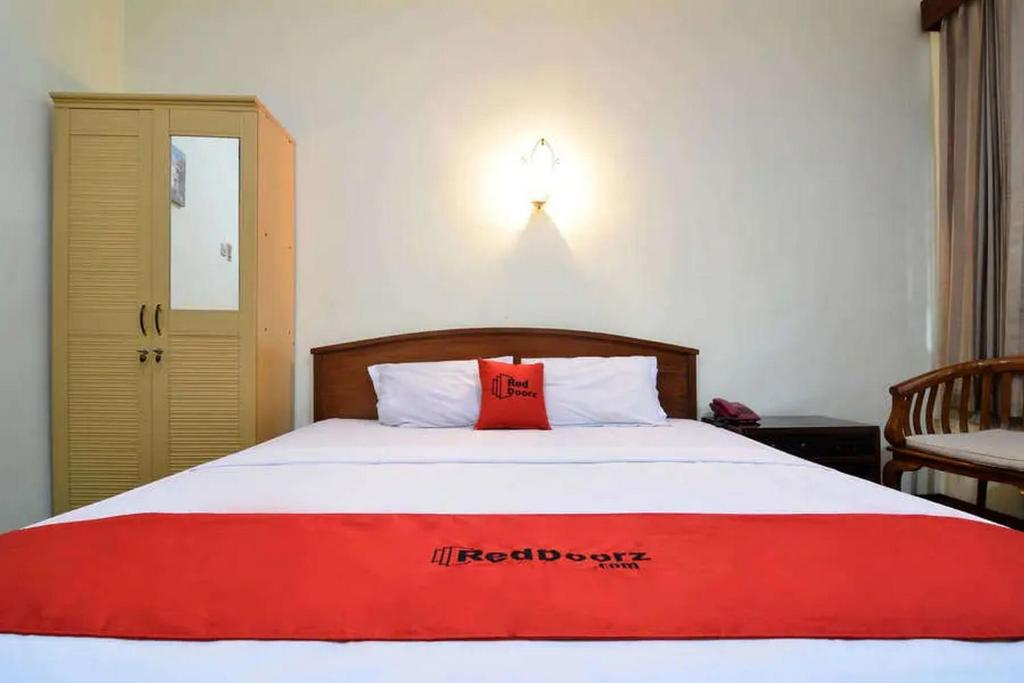 a bedroom with a bed with a red pillow on it at RedDoorz Plus @ Laweyan in Solo