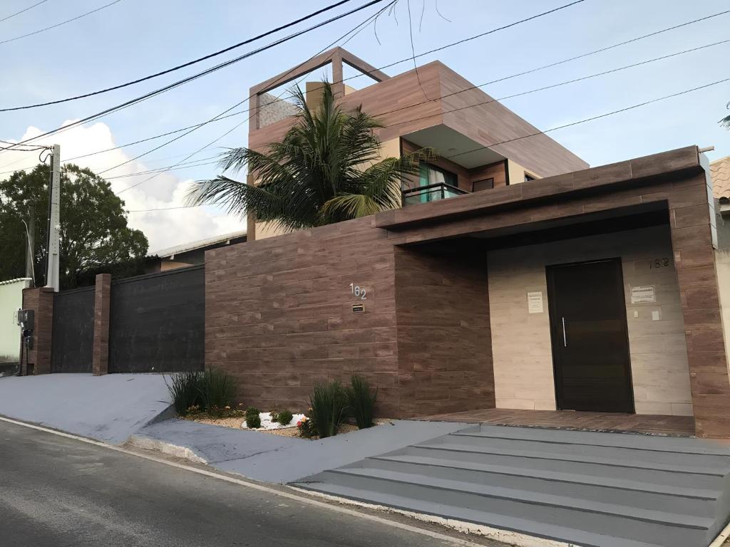 une maison avec un palmier en face dans l'établissement Pousada Dourados de Itaúna, à Saquarema