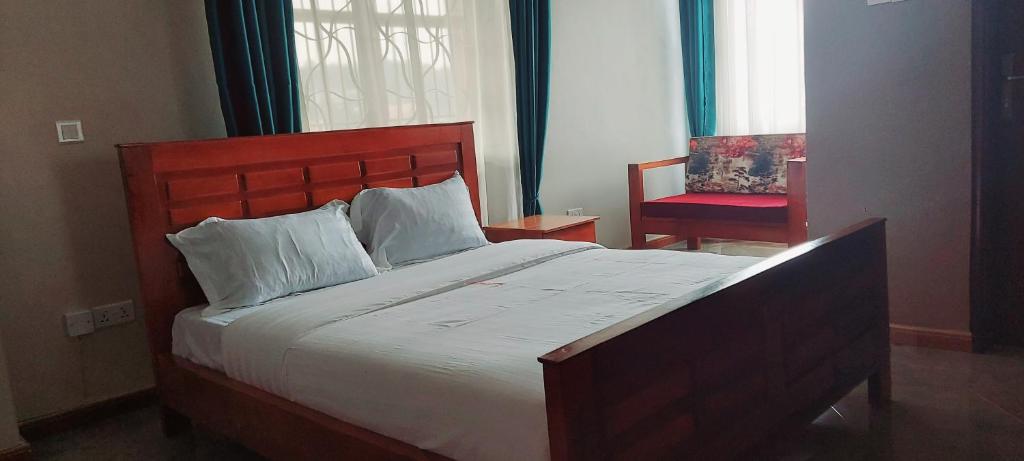 a bedroom with a large bed and a red chair at SEED HOTEL in Entebbe