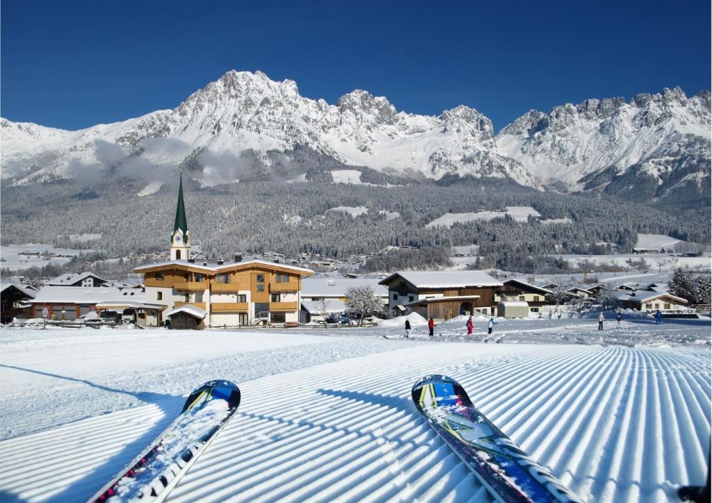 a pair of skis in the snow in front of a mountain at Alpen Chalet ELLMAU Zentrum in Ellmau