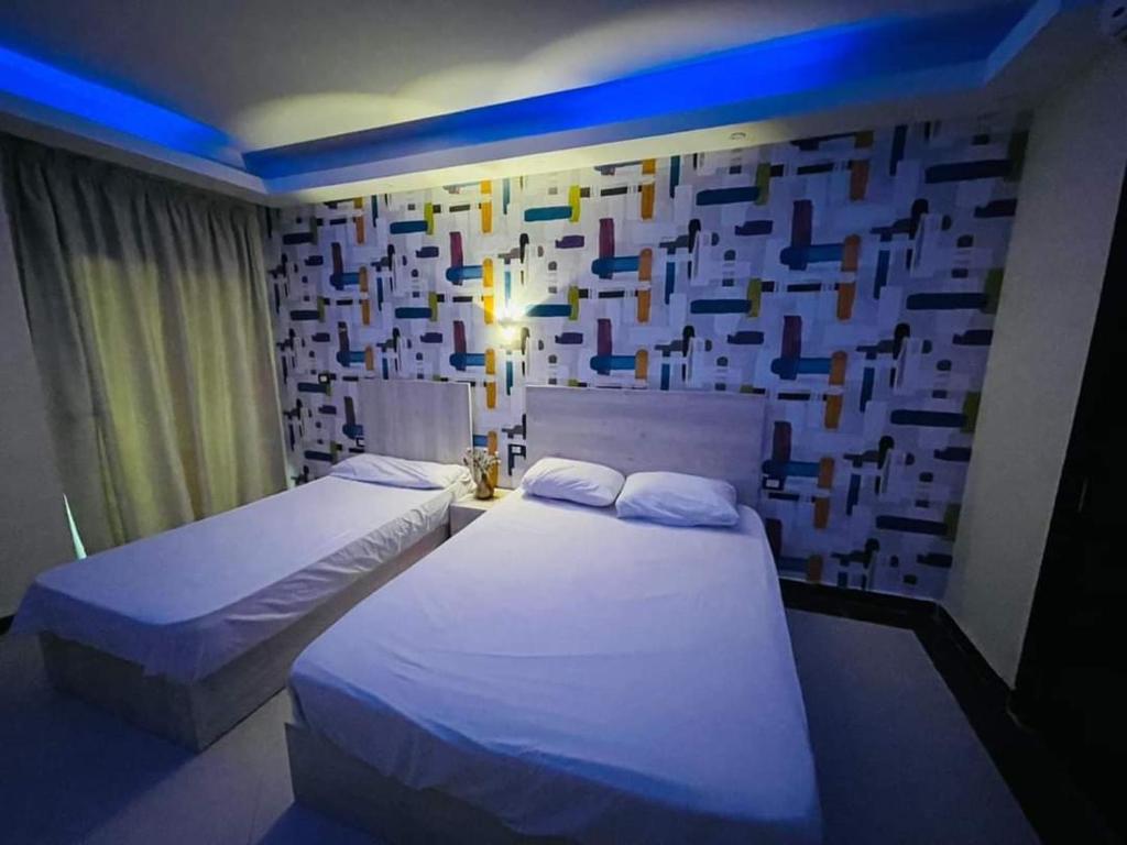 two beds in a room with a wall with squares at سيسيليا ريزورت in Hurghada