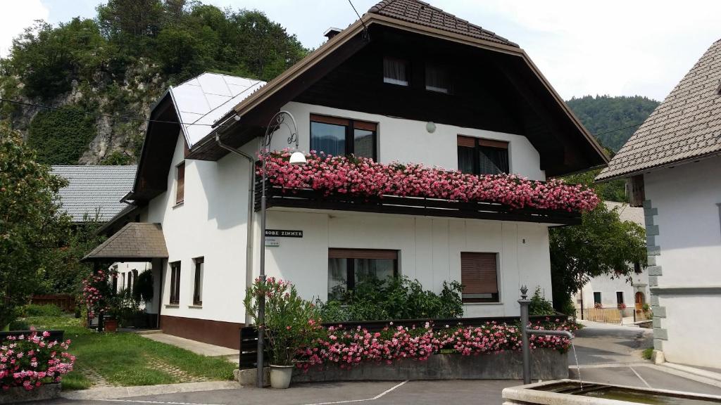 une maison blanche avec des fleurs roses sur elle dans l'établissement Apartments Gregorc, à Bled