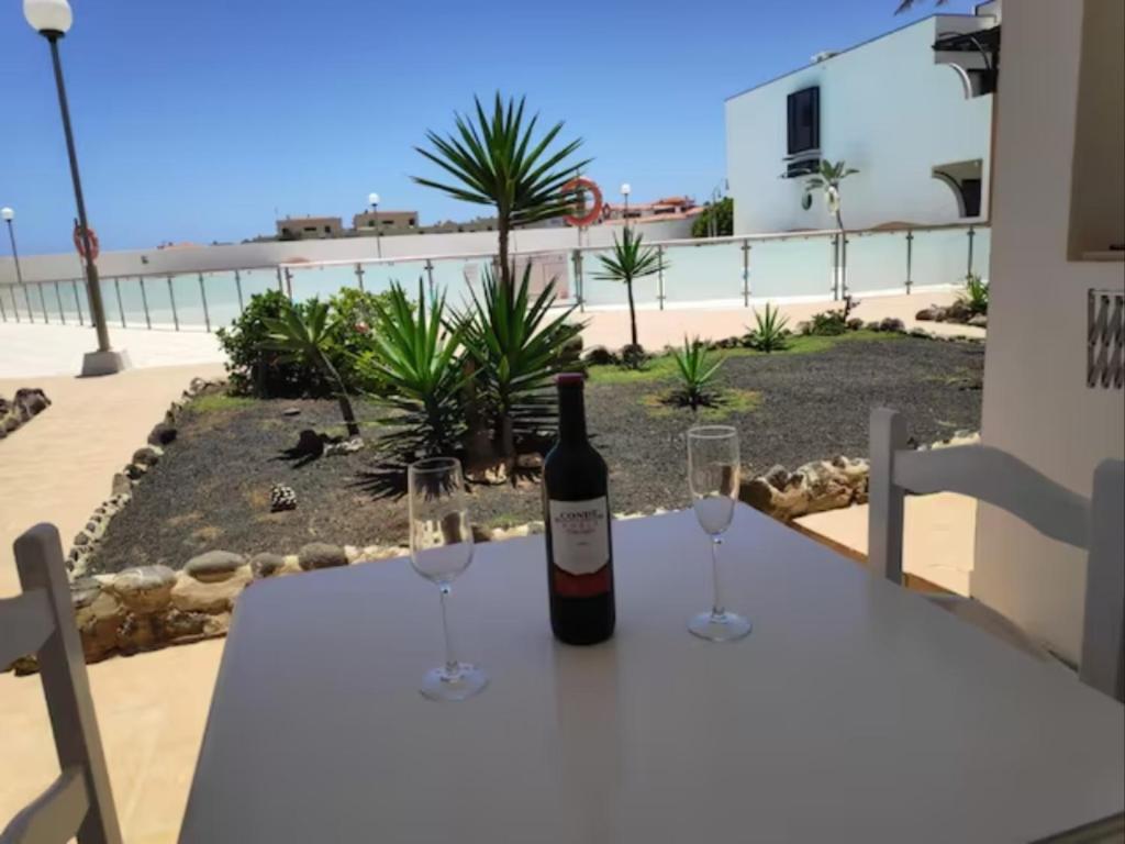 a bottle of wine sitting on a table with two glasses at Apartamento Happyness Complex Amaya Fuerteventura in Costa de Antigua