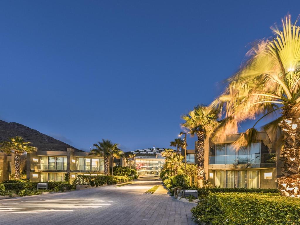 a driveway in front of a building with palm trees at Swissôtel Resort Bodrum Beach in Turgutreis