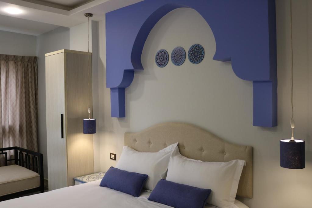 een slaapkamer met een bed met blauwe en witte kussens bij Amman Trail Hotel & Studios in Amman