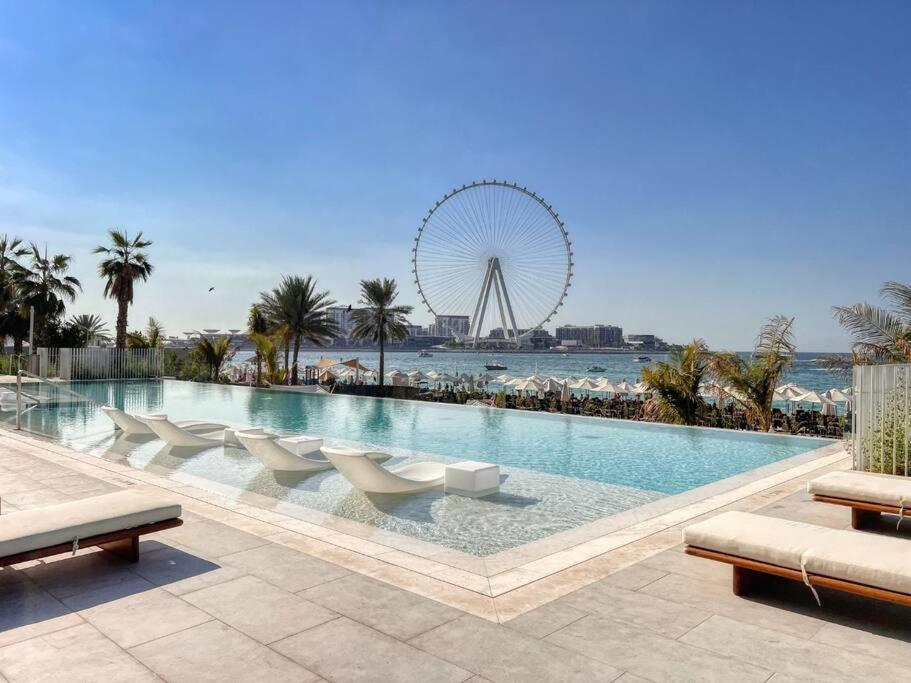 een groot zwembad met een reuzenrad op de achtergrond bij Stunning 2BR with Sea and Ain Dubai View at JBR in Dubai