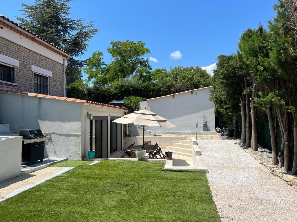 un jardin avec un parasol et une pelouse dans l'établissement la brigantine 2, à La Ciotat