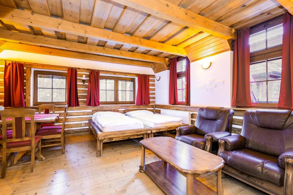 Una sala de estar con una cama, un sofá y una mesa. en Hotel Leyla, en Frymburk