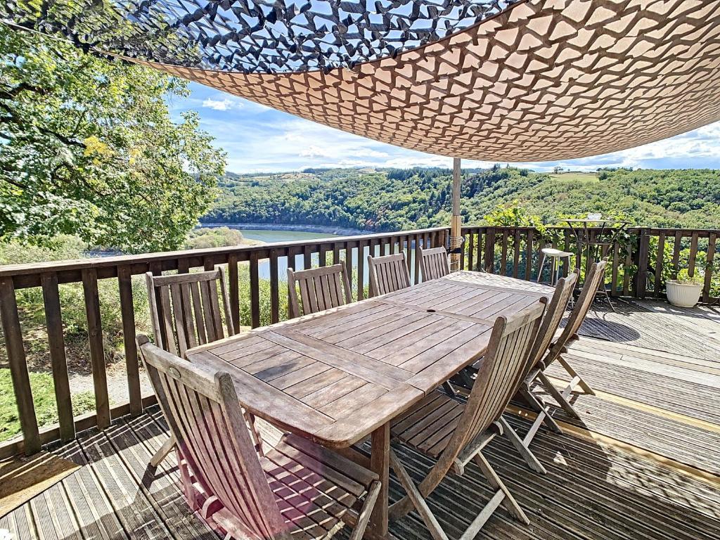 une table et des chaises en bois sur une terrasse avec un hamac dans l'établissement Ô fil de l'eau - Gîte en bord de lac, à Saint-Maurice-sur-Loire