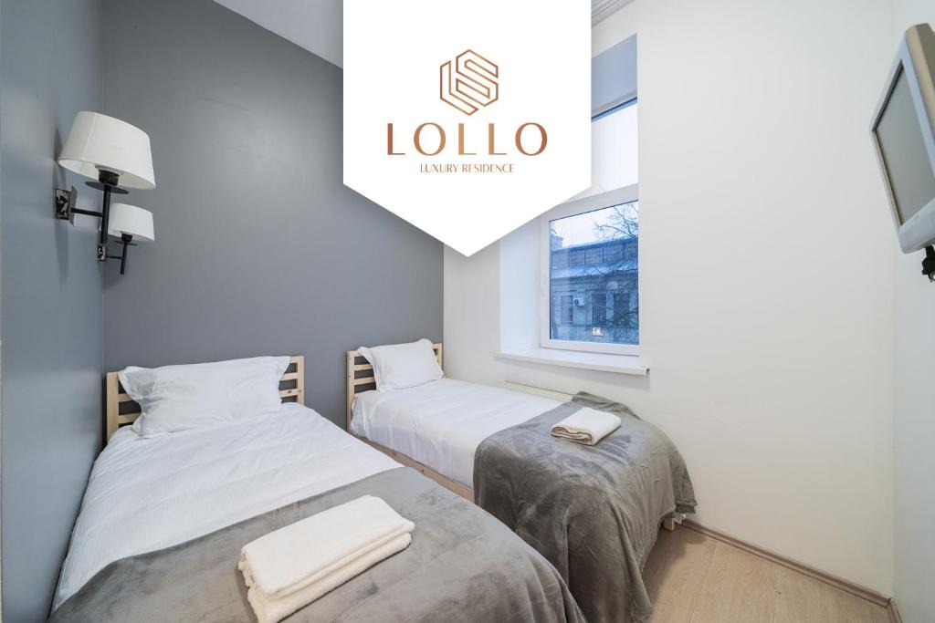 two beds in a room with a sign that reads lola at Halės Guest House - Lollo Luxury in Vilnius