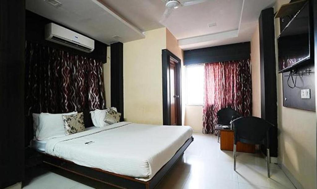 a bedroom with a bed and a desk and a window at FabHotel Madurai in Udaipur