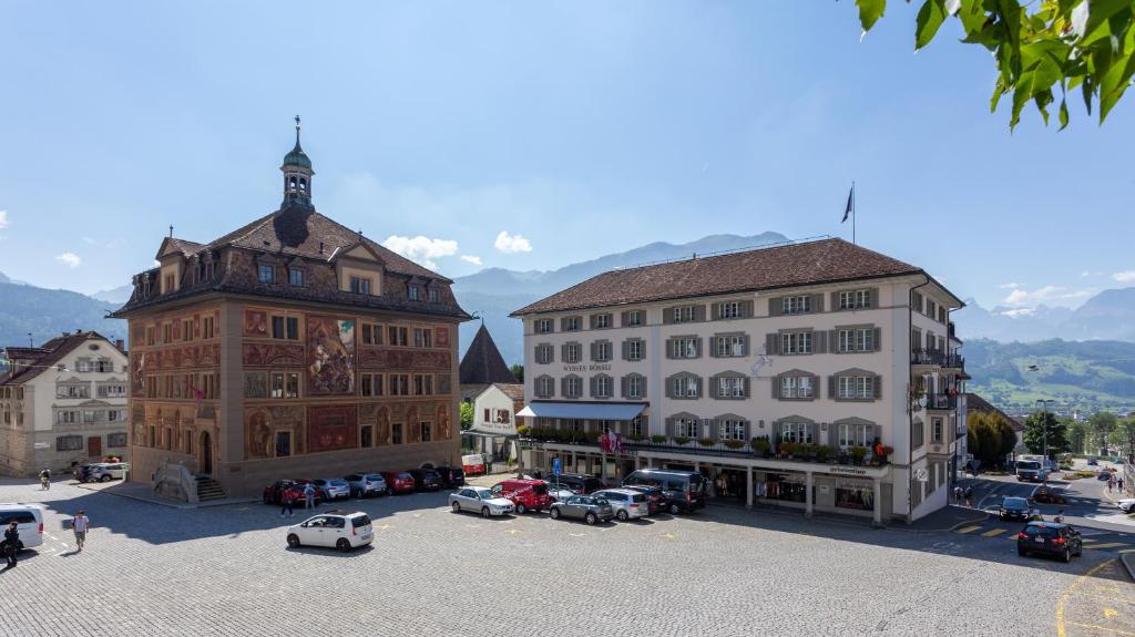 a group of buildings with cars parked in a parking lot at Wysses Rössli Swiss Quality Hotel in Schwyz