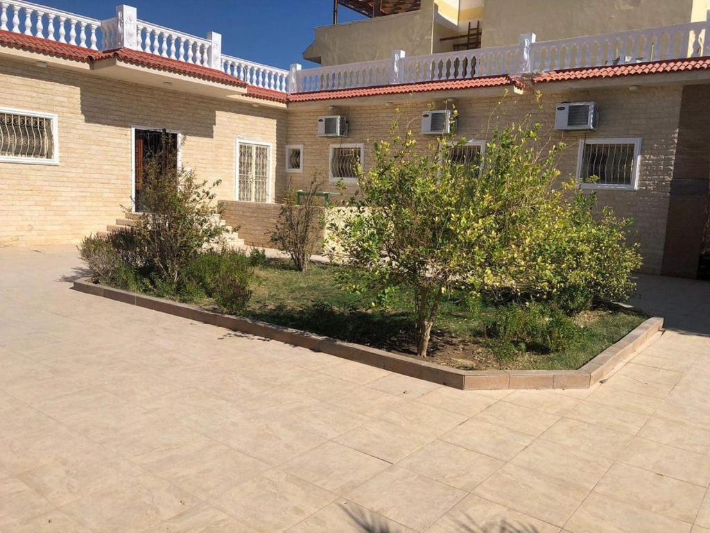 Magawish Villa hurghada في الغردقة: مبنى من الطوب مع اشجار في ساحة الفناء