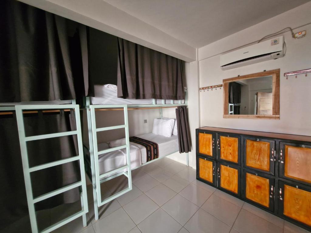 a room with two bunk beds and a mirror at Lala Salama Backpacker in Teluknarat