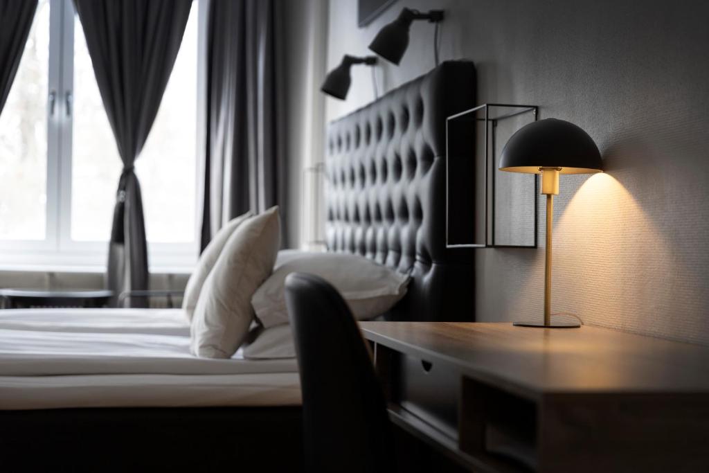 a bedroom with a bed and a desk with a lamp at Hotell Skövde in Skövde