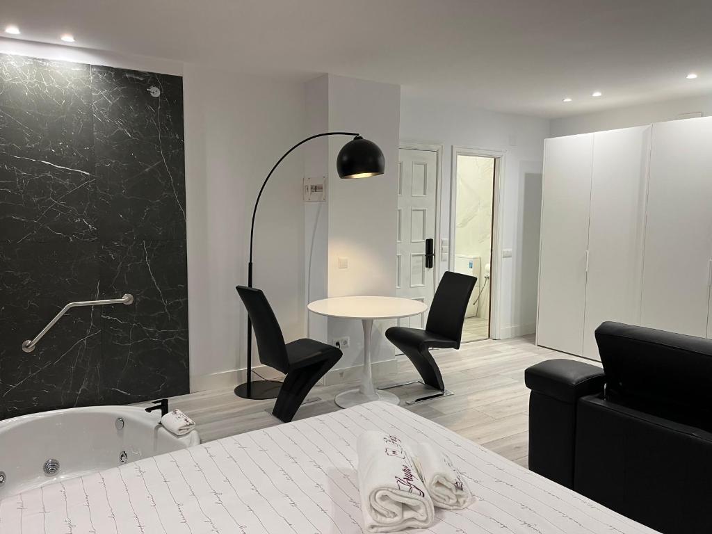 a bathroom with a tub and a table and chairs at H Pelayo Auto Check-In Rooms in Noja