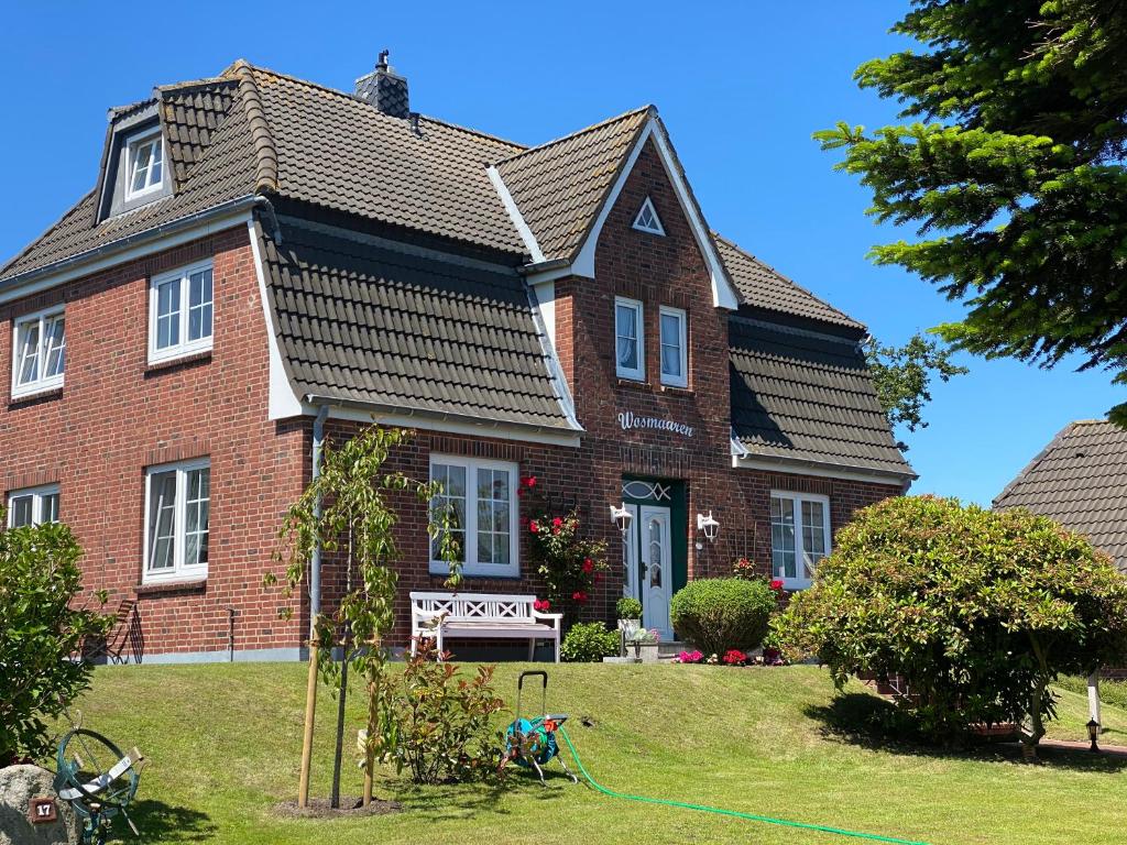 a large brick house with a roof at Pension Wosmaaren in Norddorf