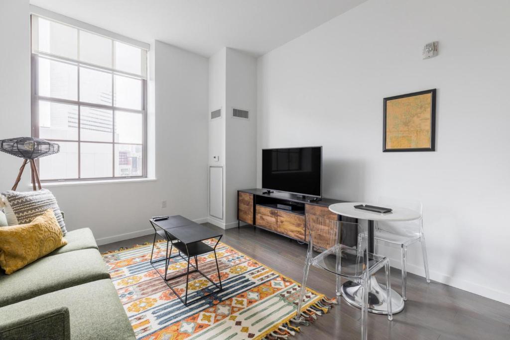 a living room with a couch and a tv and a table at Downtown studio w gym laundry nr shopping BOS-987 in Boston