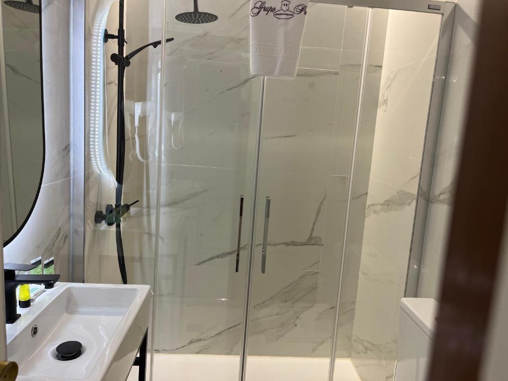 a shower with a glass door next to a sink at H Pelayo Auto Check-In Rooms in Noja
