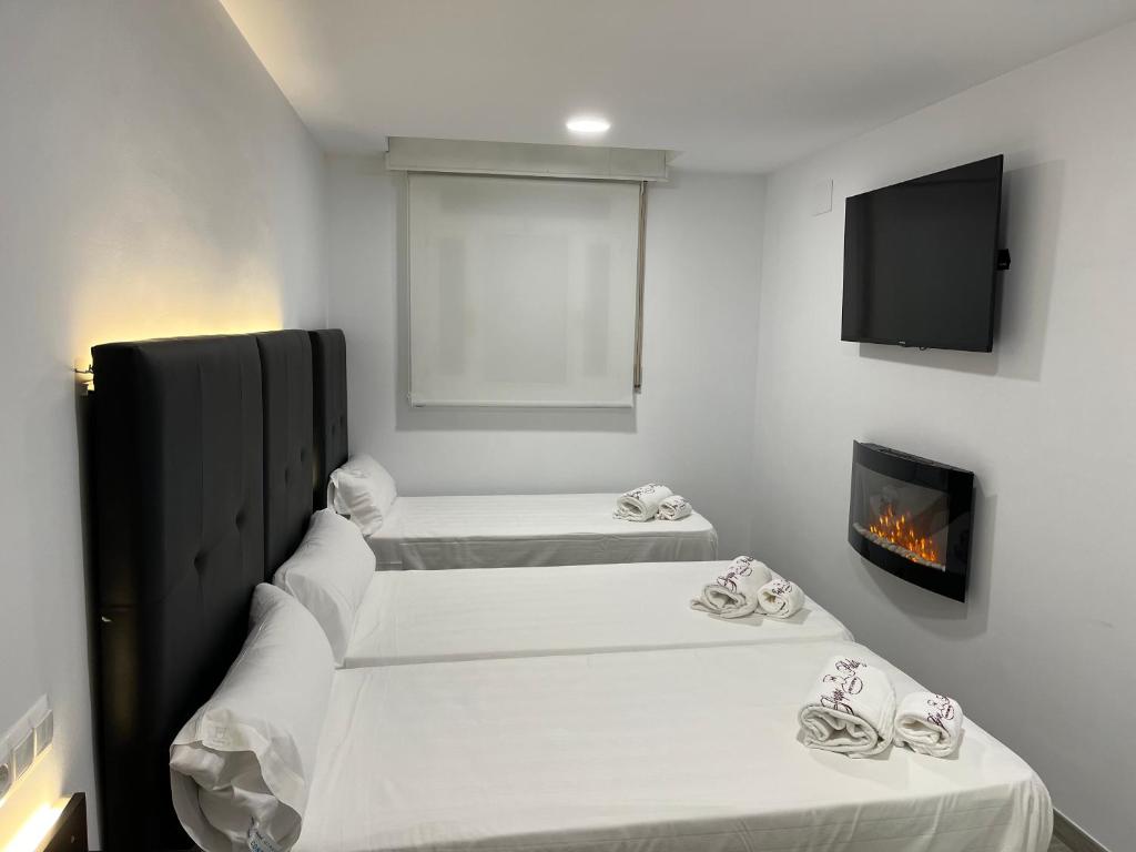 two beds in a room with a fireplace and a tv at H Pelayo Auto Check-In Rooms in Noja