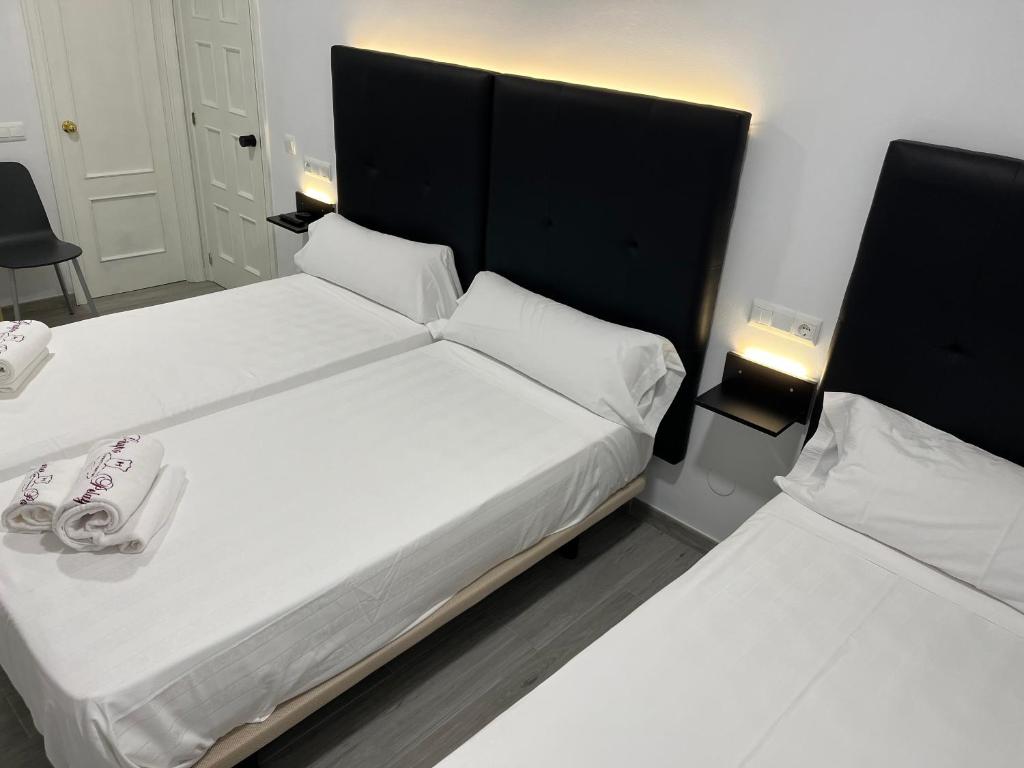 two beds in a small room with white sheets at H Pelayo Auto Check-In Rooms in Noja